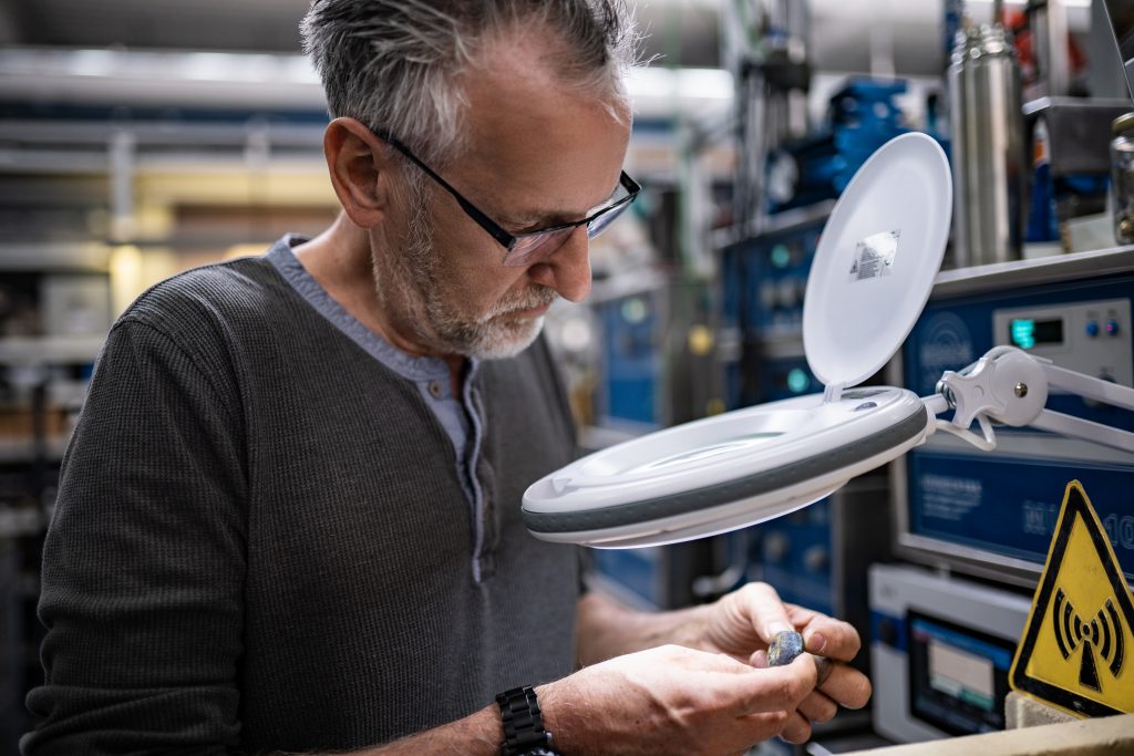 Developer looks at a workpiece under a magnifying glass in the laboratory